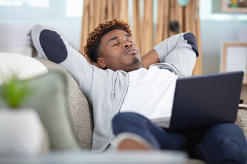 young attractive man sleeping while working with computer on couch