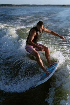 Young man wake surfing in lake against clear sky.