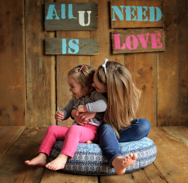 Young sisters laughing and playing indoors on weathered wood