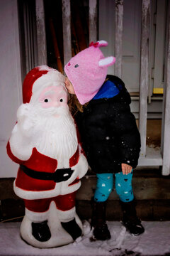Young girl kissing Santa decoration outdoors