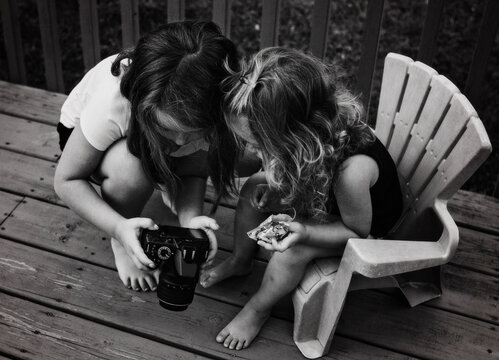 Young sisters taking photographs in back yard