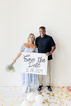 Couple holding a "Save the Date" sign with wedding date