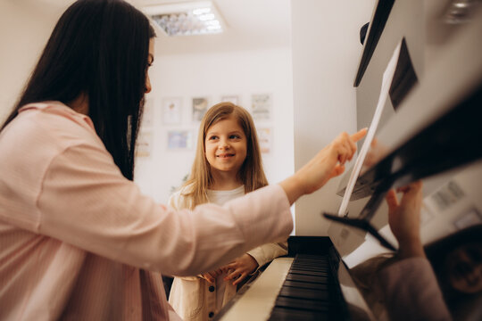 Music teacher shows how to play the piano. Girl learning play piano with teacher