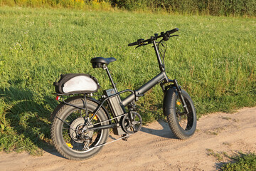 Electric folding bicycle for riding in nature in countryside. Sport and health. Summer hobby. 