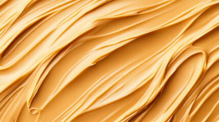 Closeup of a smooth, smeared peanut butter background with rich, creamy textures and a light golden...