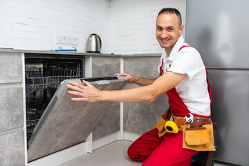 Repair of dishwashers. The master has come home and is repairing the dishwasher