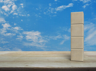 Four wood block cubes on wooden table over blue sky with white clouds