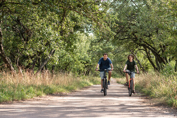 Obraz premium Family bike ride in a park at summer, father and teenager son riding on bicycles outdoor in nature