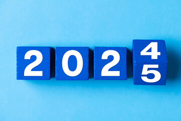 2025 Happy New Year. Wooden cube block change from 2024 to 2025 on blue. Concept 2025 New Year...
