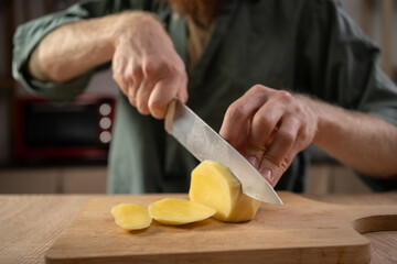 Cooking man on home kitchen. Preparation of lunch or dinner. Cutting vegetables, potatoes