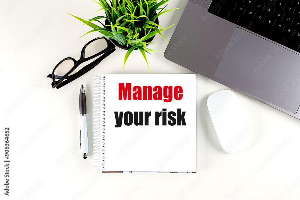 Poster manage your risk text on notebook with laptop, mouse and pen