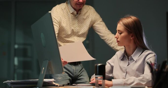 Colleague shows reports with wrong data to displeased lady boss in evening office. Angry female manager throws crumpled paper sheet in coworker