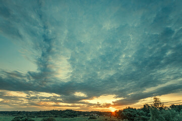 A stunning sunset of orange and gold hues paints the sky as clouds drift by. The sun sets beneath...