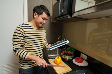 man cooking and preparing food according to a recipe on a tablet computer in kitchen at home