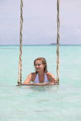 woman swinging on a swing in the ocean, Exotic Tropical Paradise Swing over Crystal Clear Turquoise Blue Ocean Seascape