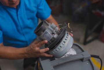 A handyman or technician removes an old or defective motor from a vacuum cleaner needing...