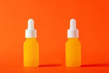 Yellow glass cosmetic bottle, Skin care or sunscreen cosmetic on orange background.