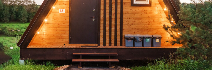 Obraz premium The concept of glamping and renting a chalet for weekend. Wooden house with a veranda in nature around coniferous trees