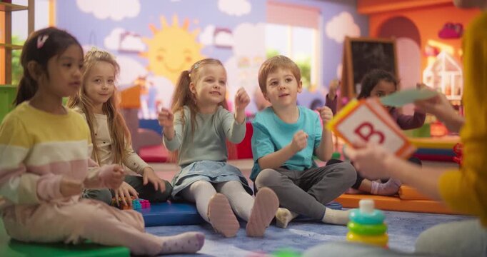 Happy Kindergarten Pedagogue Having a Conversation with Kids, Using Enthusiastic Teaching Methods in a Modern Colorful Kindergarten. Female Educator Stimulating Linguistic and Social Skills