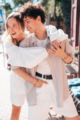 Fototapeta premium Smiling beautiful woman and her handsome boyfriend. Woman in casual summer clothes. Happy cheerful family. Female having fun. Couple posing in the street it sunny day. Cheerful and happy
