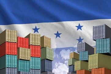 Honduras flag and big stack of shipping cargo containers in docks with sky background close up
