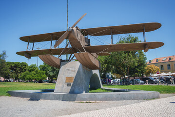 A biplane replica on a concrete pedestal in a Lisbon park, honoring the 1922 South Atlantic flight....