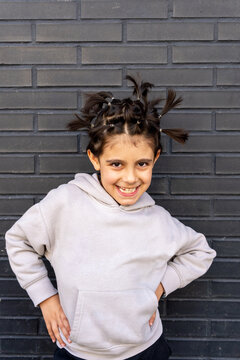 Young boy with creative pigtail hairstyle against brick wall