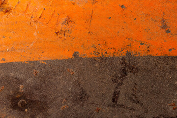 The texture of metal coated with orange paint and rust
