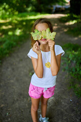 Young Girl Playfully Hiding Her Face With Leaves in Natural Forest Setting