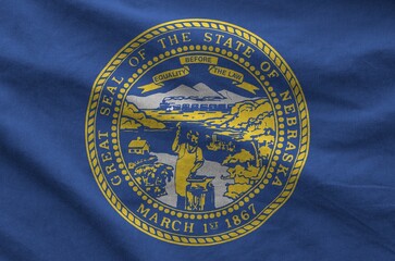 Nebraska US state flag depicted on folded wavy fabric of old cloth close up