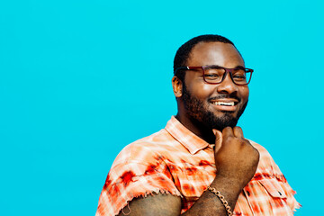 Portrait of a happy man in orange shirt smiling and thinking with hand on chin at camera, with blue copy space around him.