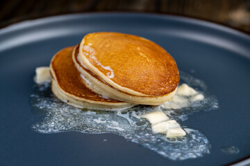 thin hot pancakes with butter on a blue plate