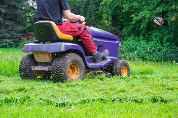 Obraz premium Man mowing lawn with riding lawn mower. Gardener showing thumbs up and smiling. Back view