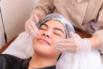 Rubbing in hyaluronic acid serum prior to a high frequency facial treatment at a spa.