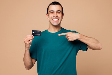 Young happy middle eastern man wear blue t-shirt casual clothes hold in hand point finger on mock...