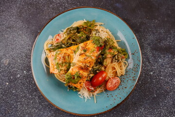 Salmon Fillet in creamy sauce with spaghetti, cream cheese and spinach and cherry tomatoes close-up on plate