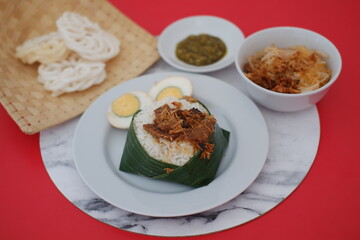 rice with meat, egg, crackers, sambal and noodles on a red background