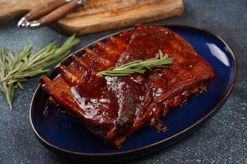 Closeup of pork ribs grilled with BBQ sauce and caramelized in honey. Grilled pork ribs with spices on a stone background