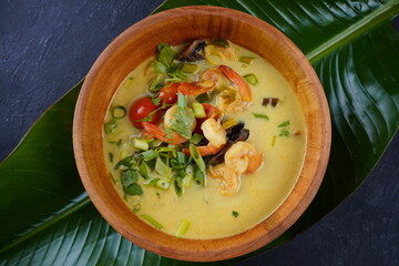 Tom Yam kung Spicy Thai soup with shrimp, seafood,tomatoes, mushrooms, lemongrass, coconut milk, ginger and chili pepper in bowl . Traditional Thai food