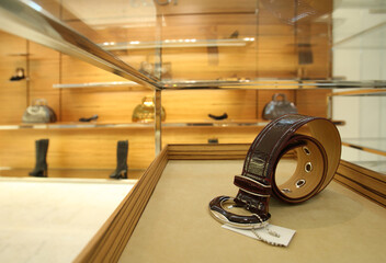 Luxurious leather belt with silver buckle displayed on a stylish mannequin in a high-end fashion boutique. Focus on the belt's craftsmanship and intricate details.