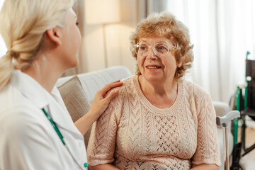 Female doctor comforting senior patient listening during home visit