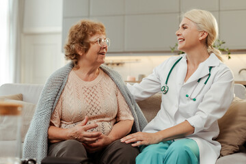 Obraz premium Female doctor comforting senior patient during home visit