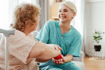 Young nurse assisting happy senior woman with physical therapy using stress ball