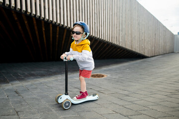 Cute little boy riding his kick scooter in the port of Tallinn. Active leisure for small kids © MNStudio