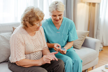 Nurse showing blood glucose meter to senior woman at home