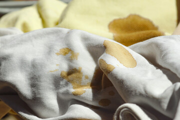 Crumpled fabrics with stains - close-up photo. Light cotton items stained with dark stains from...