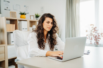 Fototapeta premium Young caucasian business woman working in office on laptop 