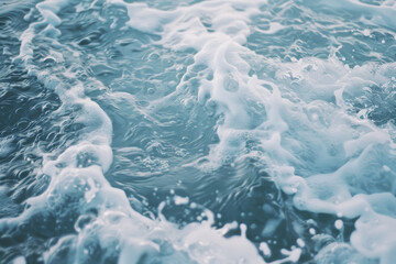 Gentle waves cresting with soft, white foam roll across an aquamarine sea, creating a soothing and calming ocean scene.