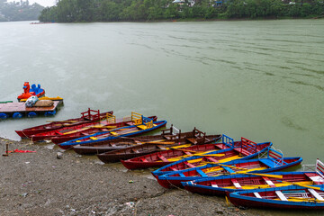 Empty boats lined up on the lakeside at Bhimtal Lake during the monsoon season, an off-season...
