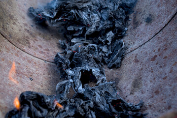Pile of burned paper on a brown background.